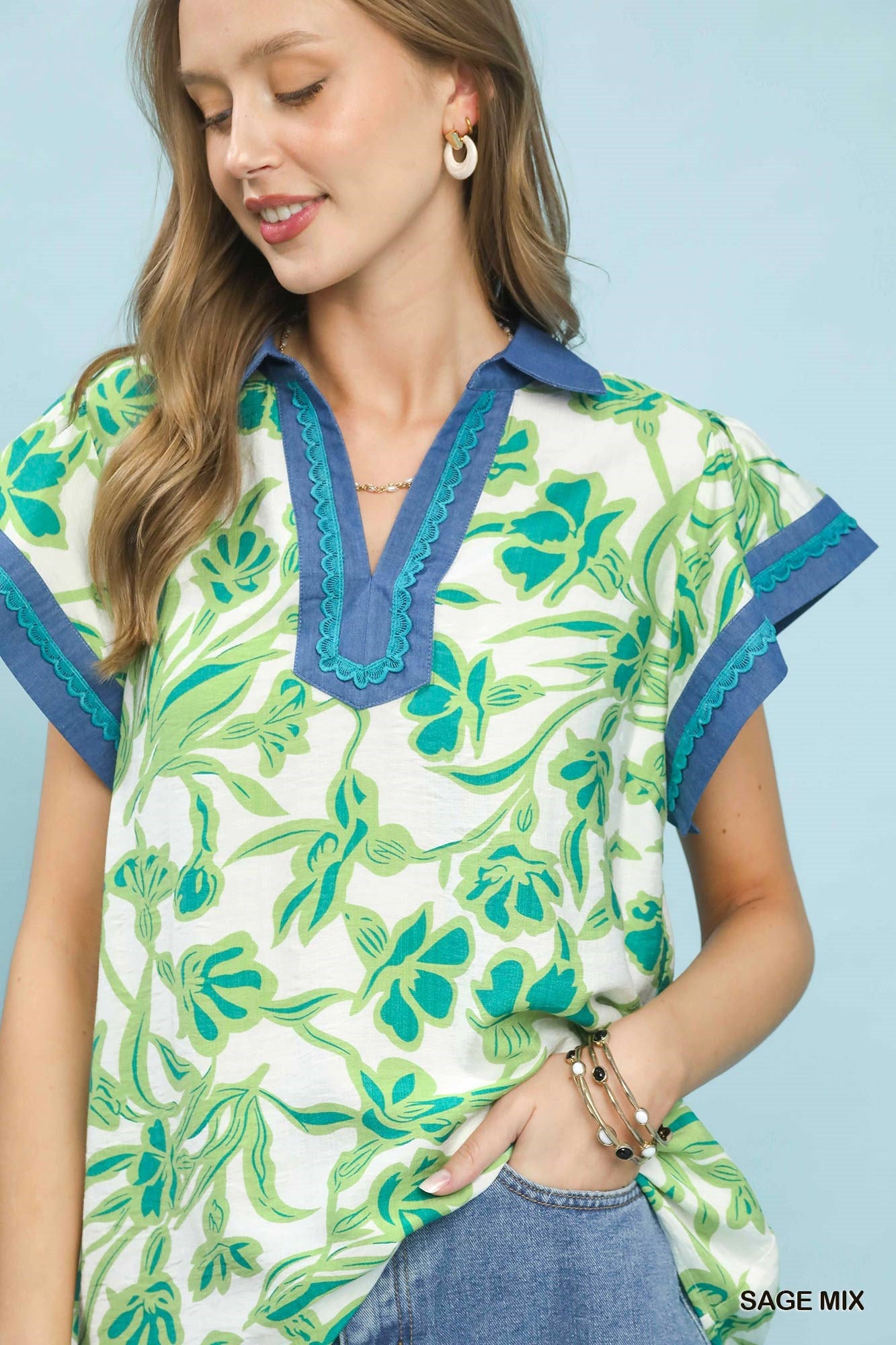 Woman wearing a floral patterned top with blue accents on a light blue background