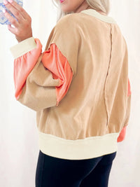 Person wearing a beige and pink jacket with a white background