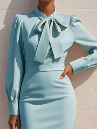 Light blue dress with a large bow detail on a neutral background