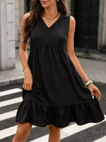 Woman wearing a black sleeveless dress on a city street.