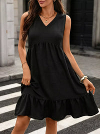 Woman wearing a black sleeveless dress on a city street.