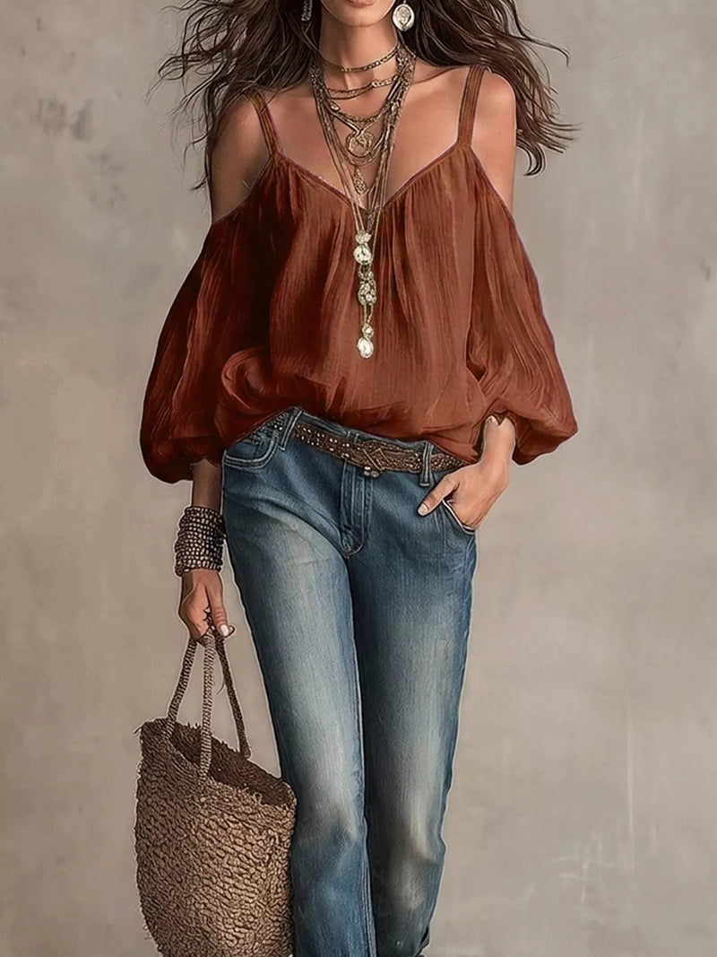 Woman wearing a brown top and blue jeans, holding a woven bag against a neutral background