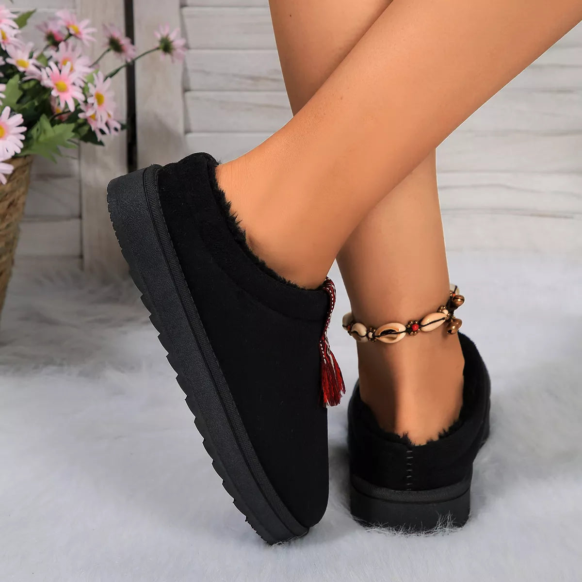 Black slippers worn by a person with a blurred background