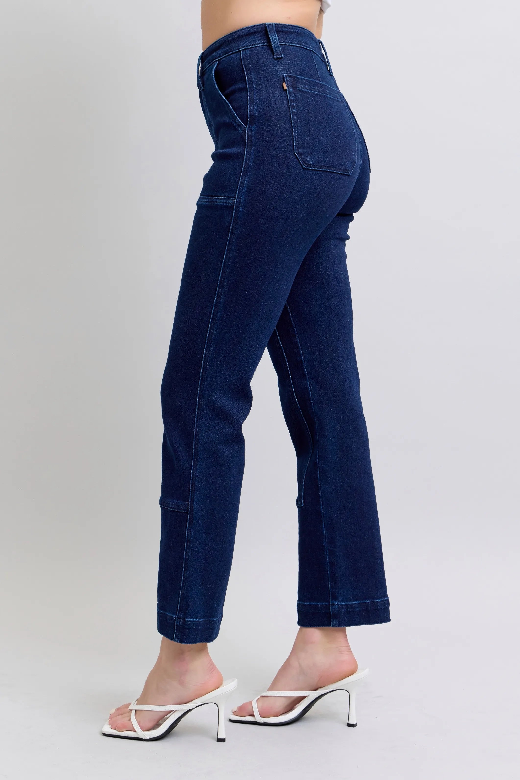 Navy blue jeans worn by a person on a plain background