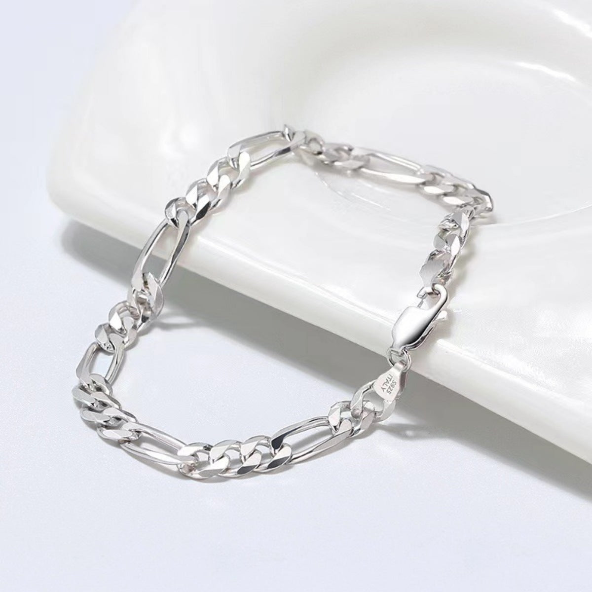 Silver chain bracelet on a white ceramic dish