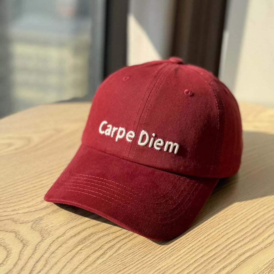 Red cap with 'Carpe Diem' text on a wooden surface