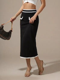 Person wearing a black skirt with white trim, holding a handbag on a beige background
