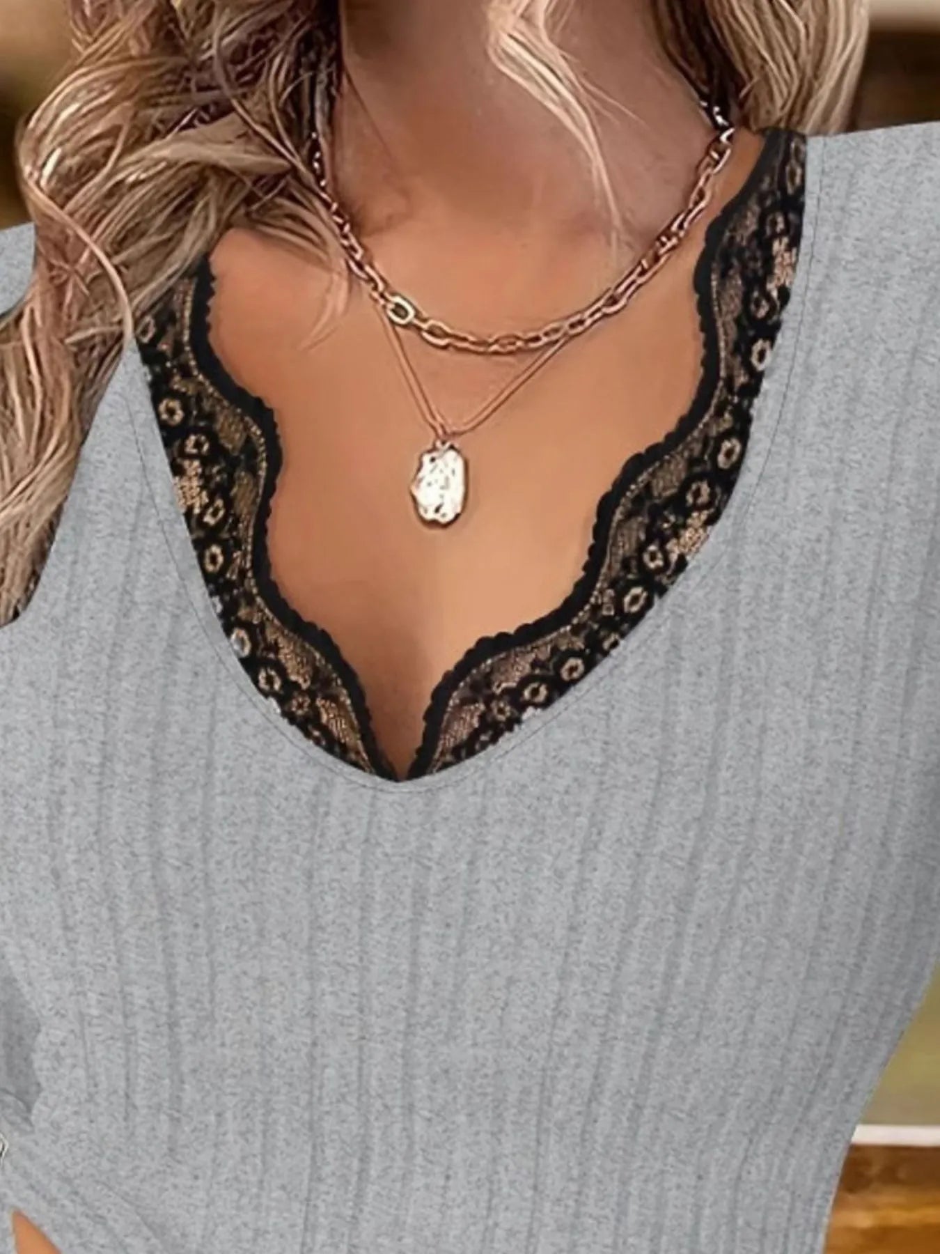 Gray ribbed sweater with black lace neckline and layered necklaces.