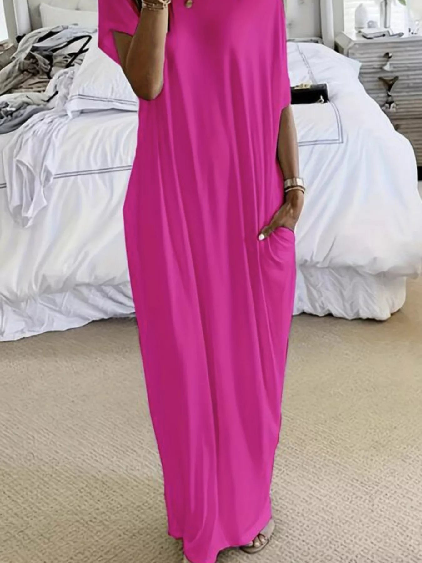 Person wearing a bright pink dress standing in a bedroom.