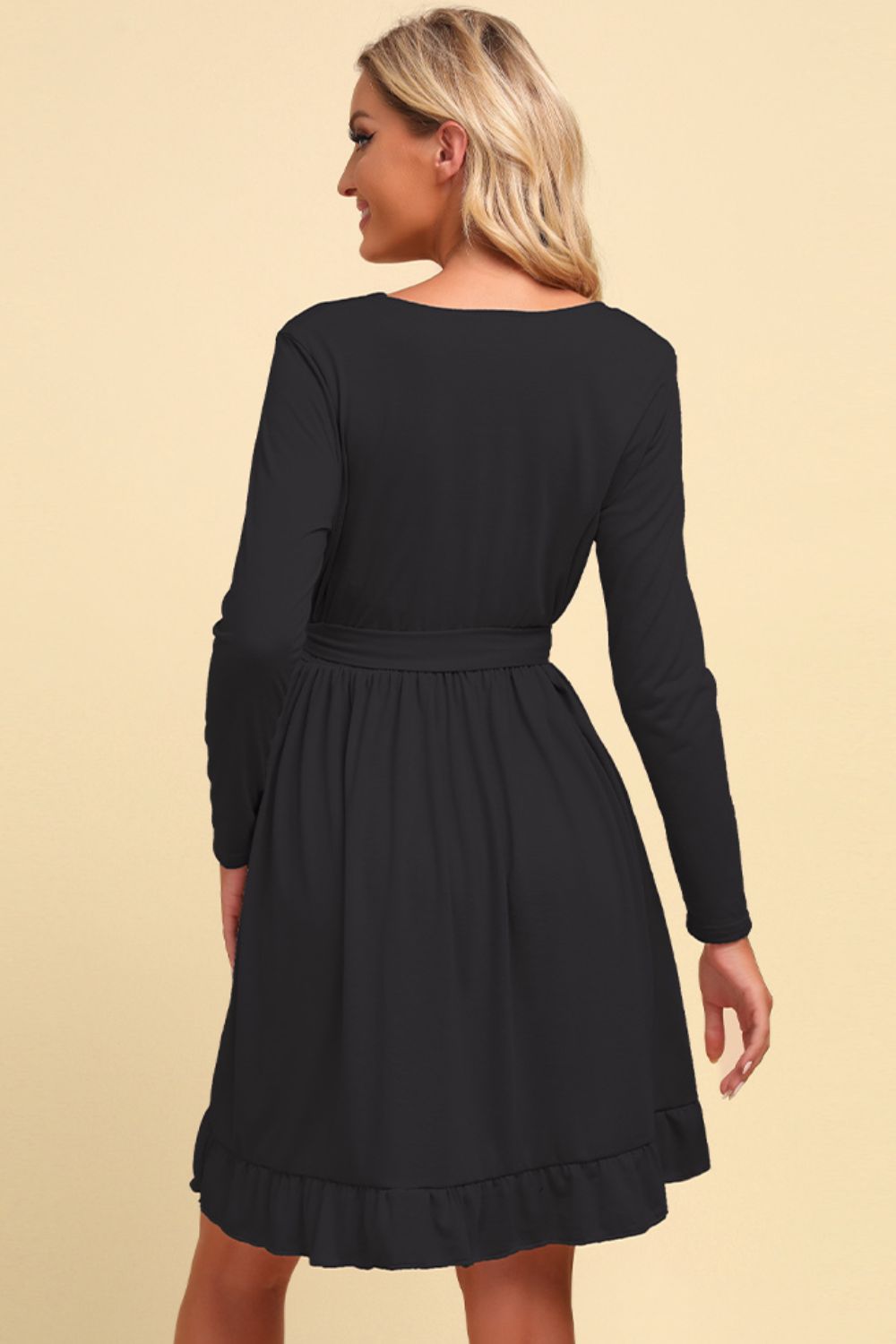 Black dress worn by a model on a beige background