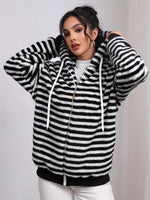 Woman wearing a black and white striped hoodie against a plain background
