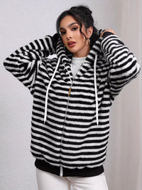 Woman wearing a black and white striped hoodie against a plain background