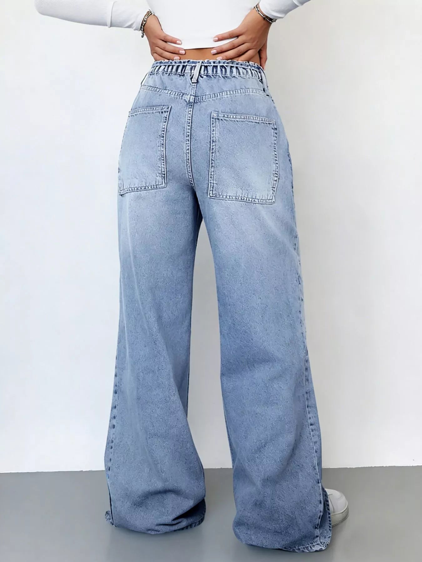 Light blue jeans worn by a person on a plain background