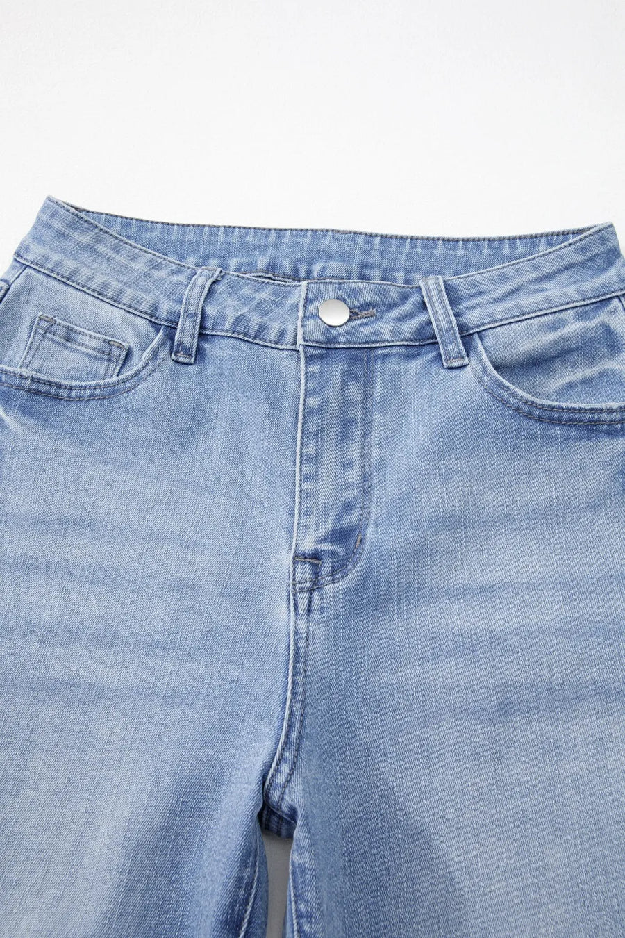 Close-up of a pair of light blue jeans on a white background