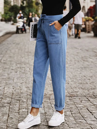 Person wearing blue jeans and white sneakers on a street.