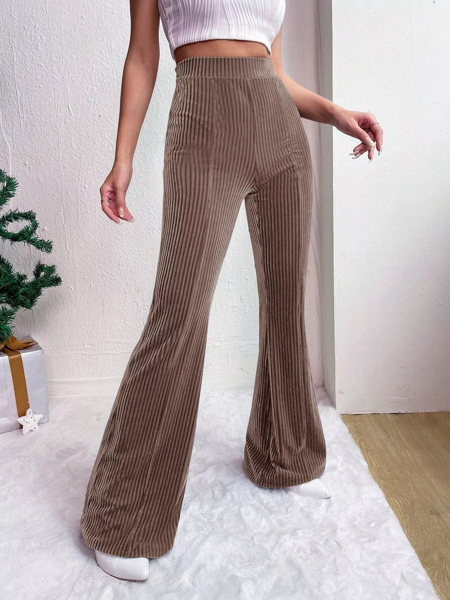Person wearing brown ribbed wide-leg pants with a white top and white shoes on a light background.