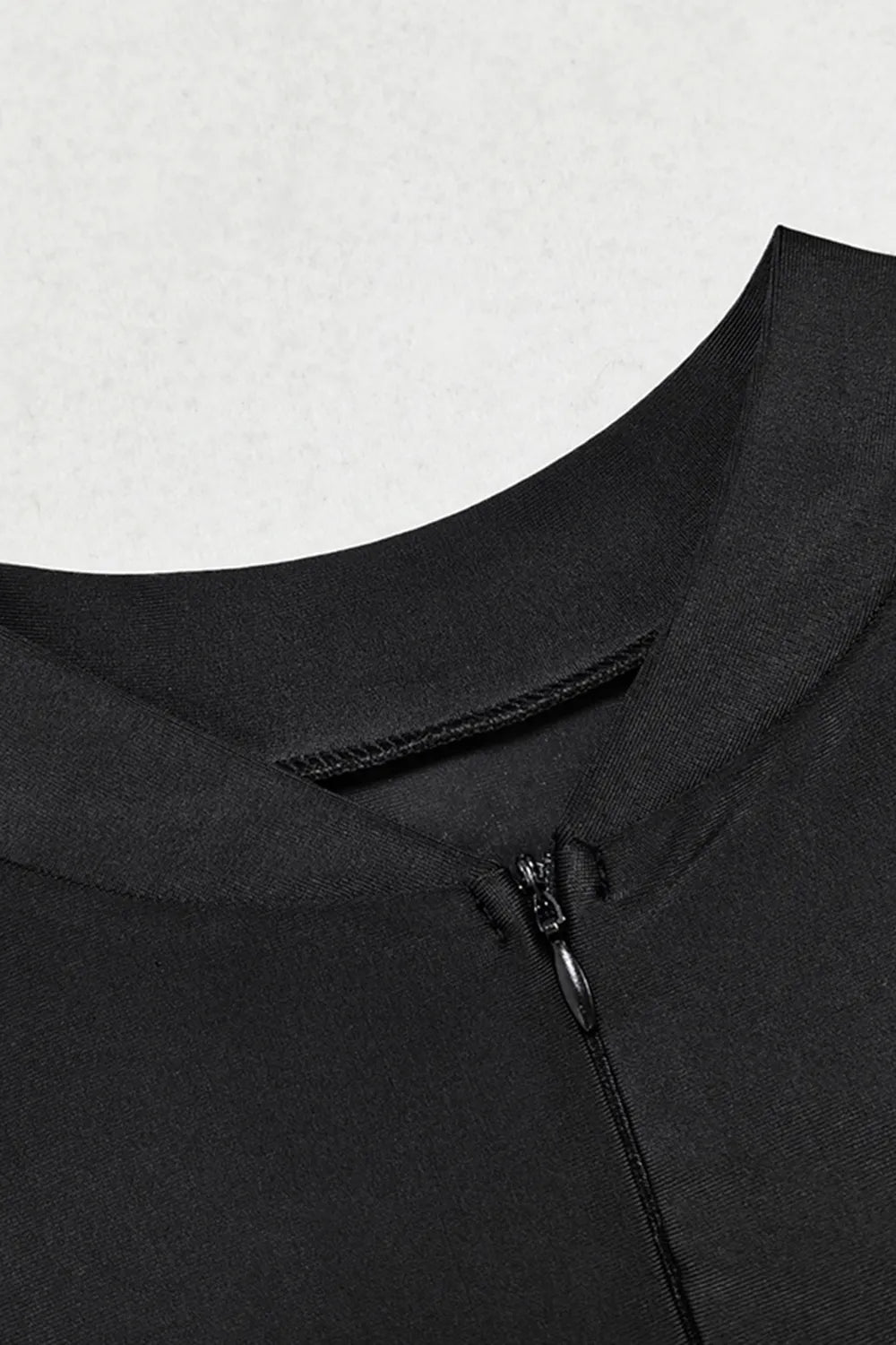 Close-up of a black garment with a zipper on a light gray background