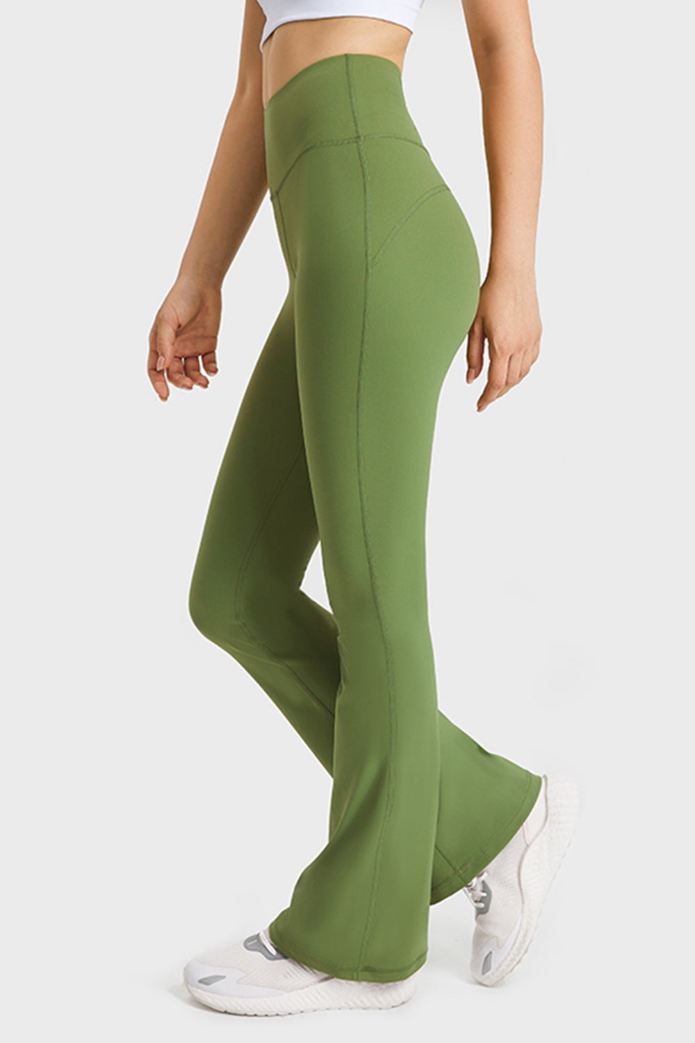 Green flared pants worn by a person on a white background