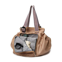 Brown tote bag with open compartment showing sunglasses and a cream-colored item on a white background