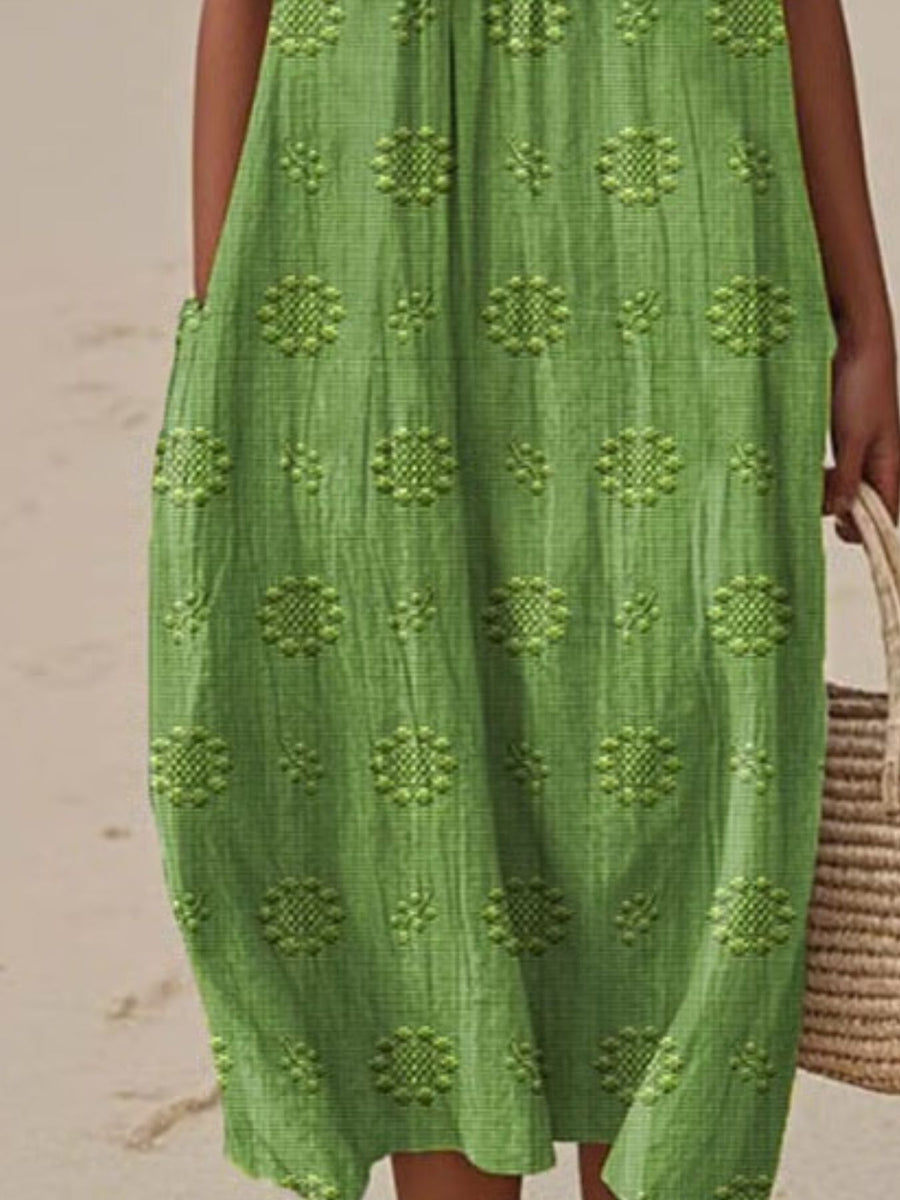 Green patterned dress worn by a person on a beach.