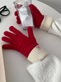 Red and white gloves on a surface with a glass of water and sunglasses.