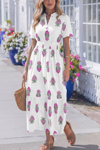 Woman wearing a white dress with pink floral pattern in an outdoor setting.