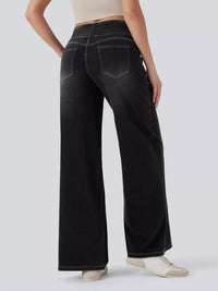 Person wearing black wide-leg jeans on a light gray background