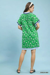 Woman wearing a green dress with white patterns on a light blue background