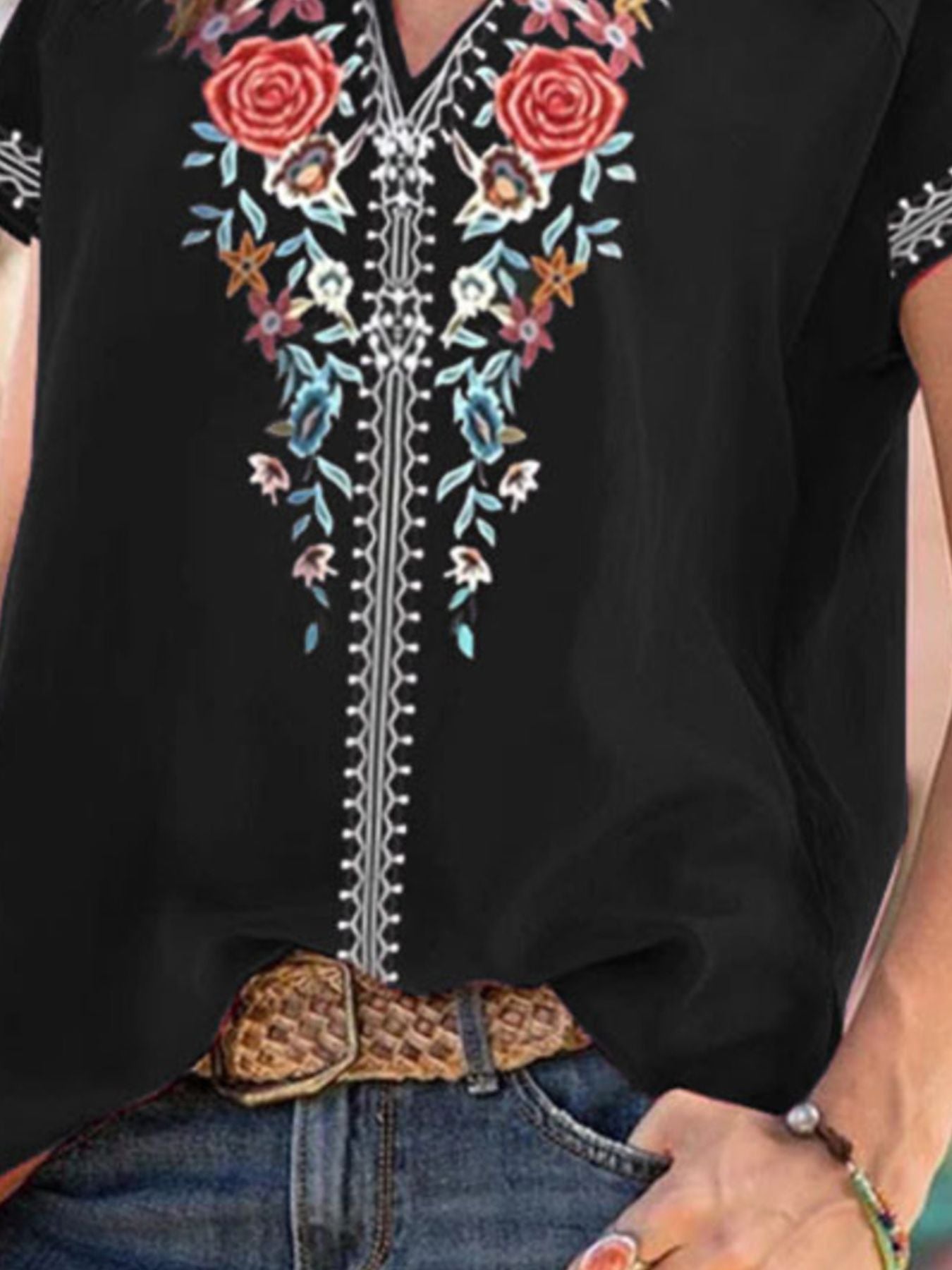 Black blouse with colorful floral embroidery and a leopard print belt.