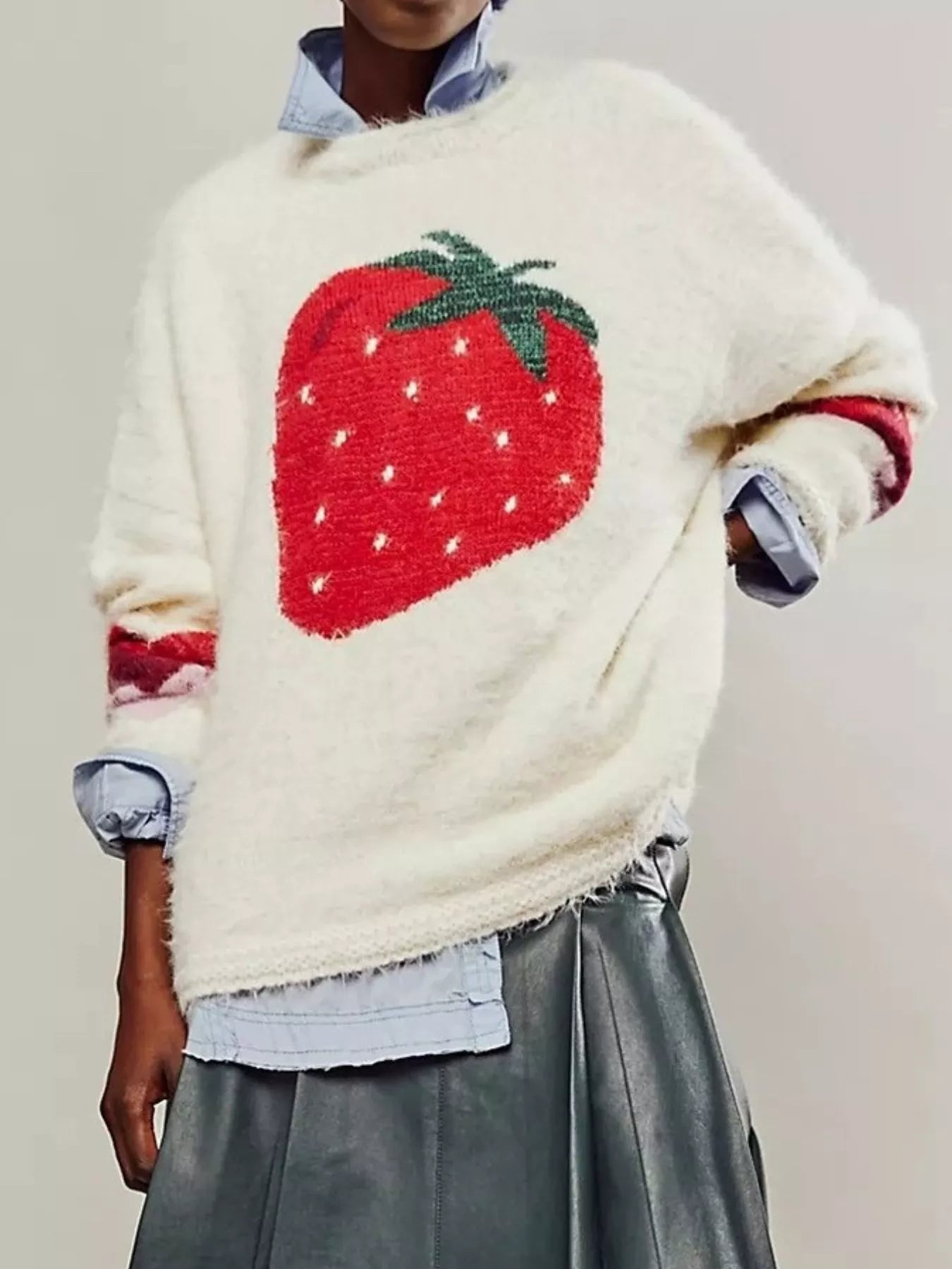 Person wearing a sweater with a strawberry design on a plain background