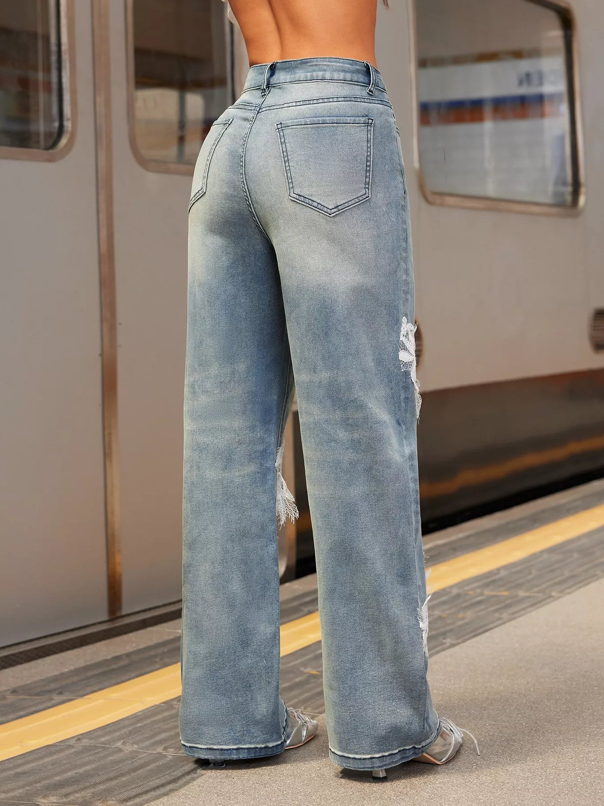 Person wearing light blue jeans on a train platform