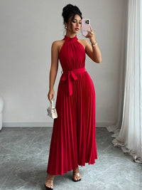 Woman in a red dress taking a mirror selfie in a room with gray walls and white curtains.