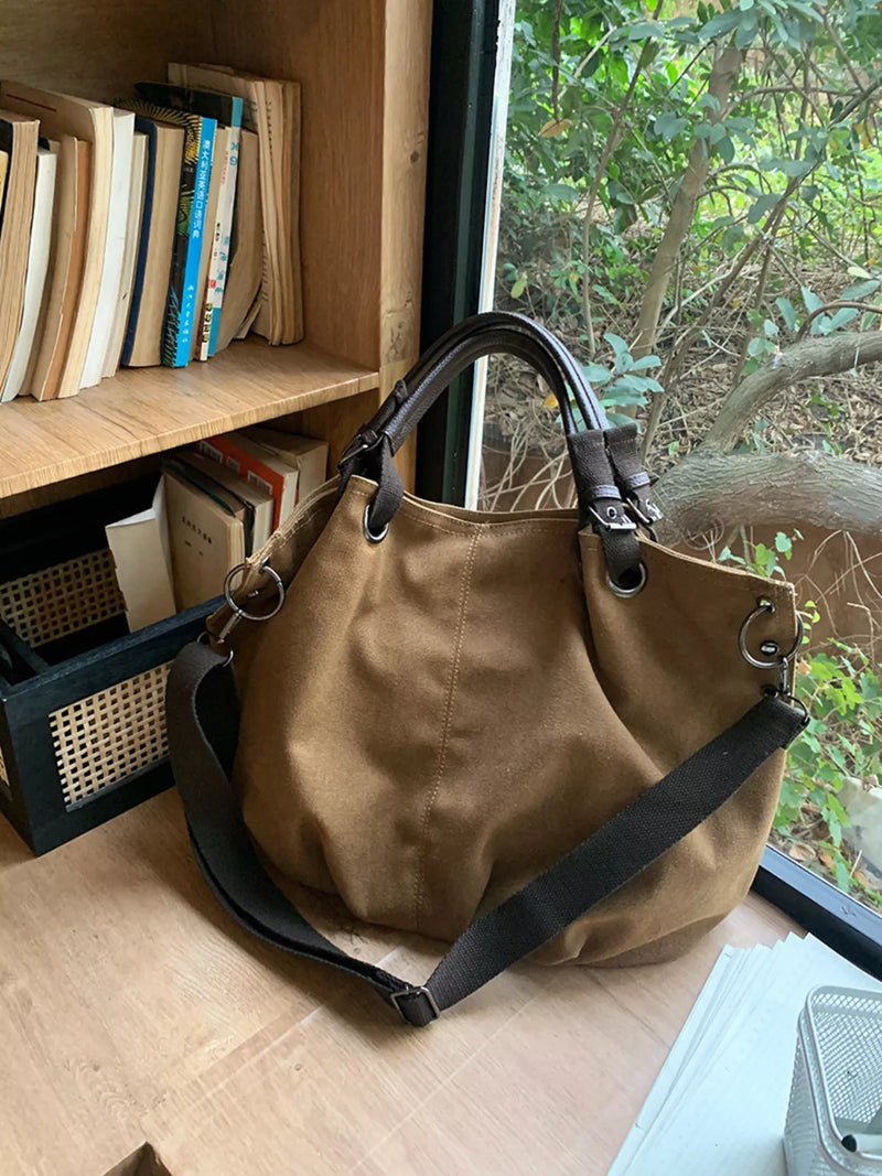 Brown handbag on a wooden surface with books and a window in the background