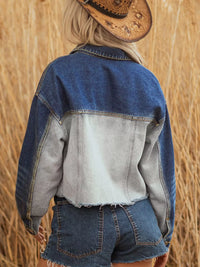 Person wearing a denim jacket and shorts with a straw hat, standing in a field.