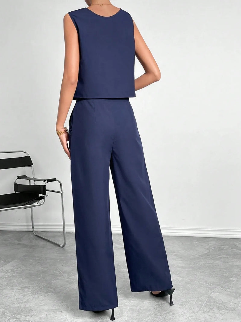 Person wearing a navy blue sleeveless top and wide-leg pants against a plain background.