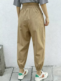 Person wearing beige high-waisted pants with a plain background