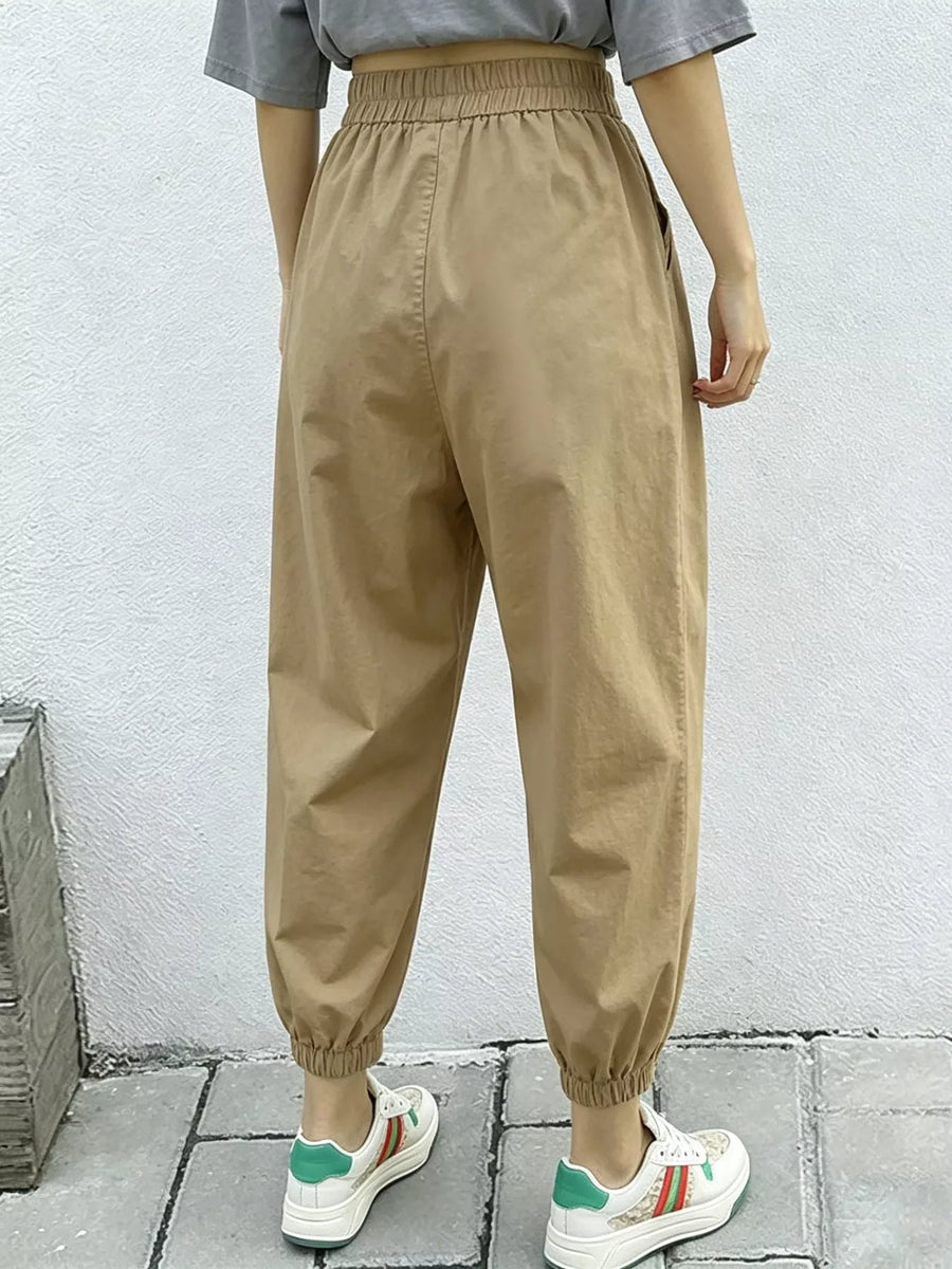 Person wearing beige high-waisted pants with a plain background
