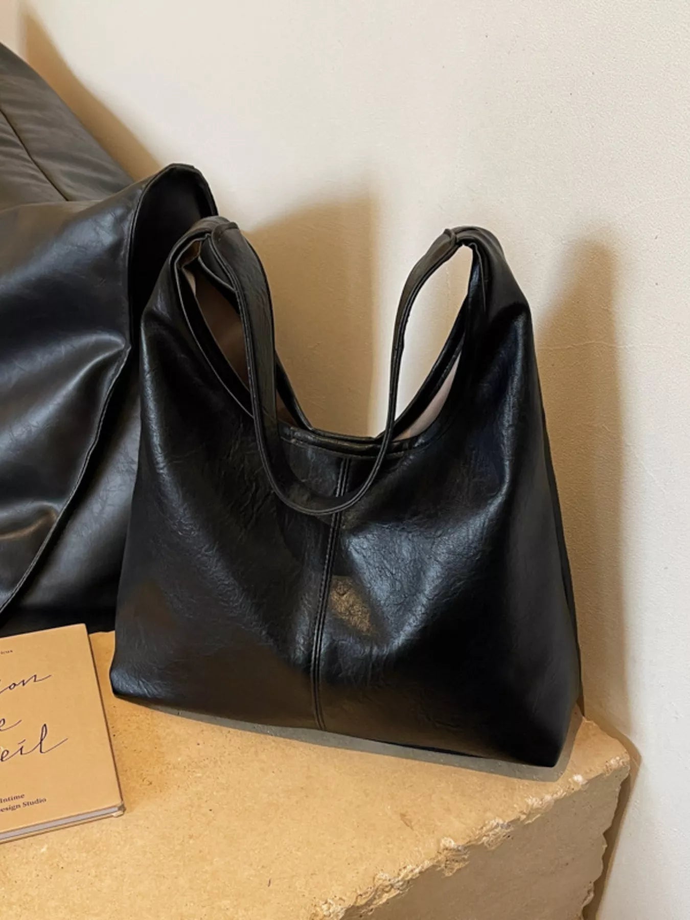 Black leather handbag on a textured surface with a neutral background
