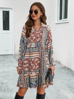 Woman wearing a patterned dress standing on a sidewalk.