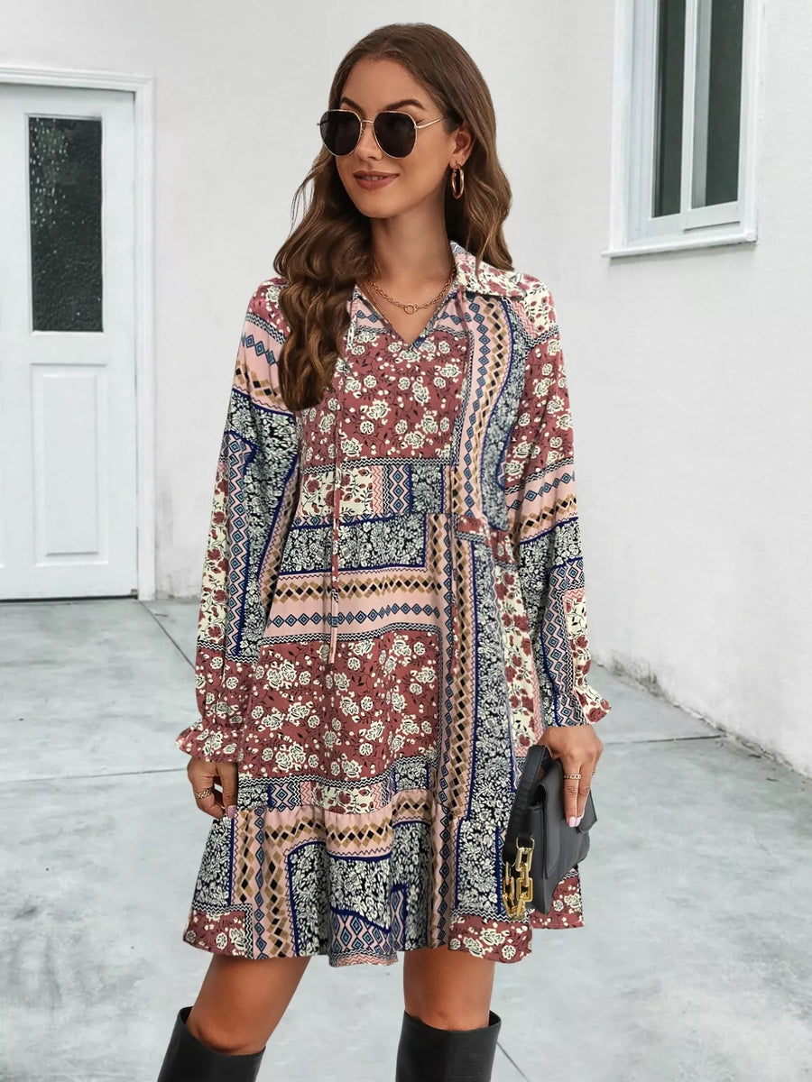 Woman wearing a patterned dress standing on a sidewalk.
