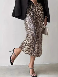 Person wearing a leopard print skirt with a black blazer and high heels on a plain background