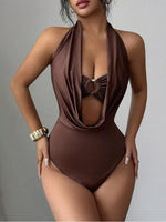 Brown halter neck swimsuit worn by a model on a gray background