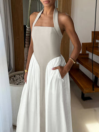 Woman wearing a beige halter neck dress with a white overlay in an indoor setting.