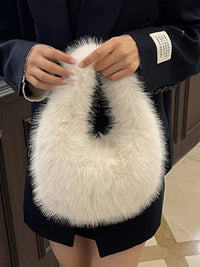 Person holding a fluffy white handbag with a black interior.