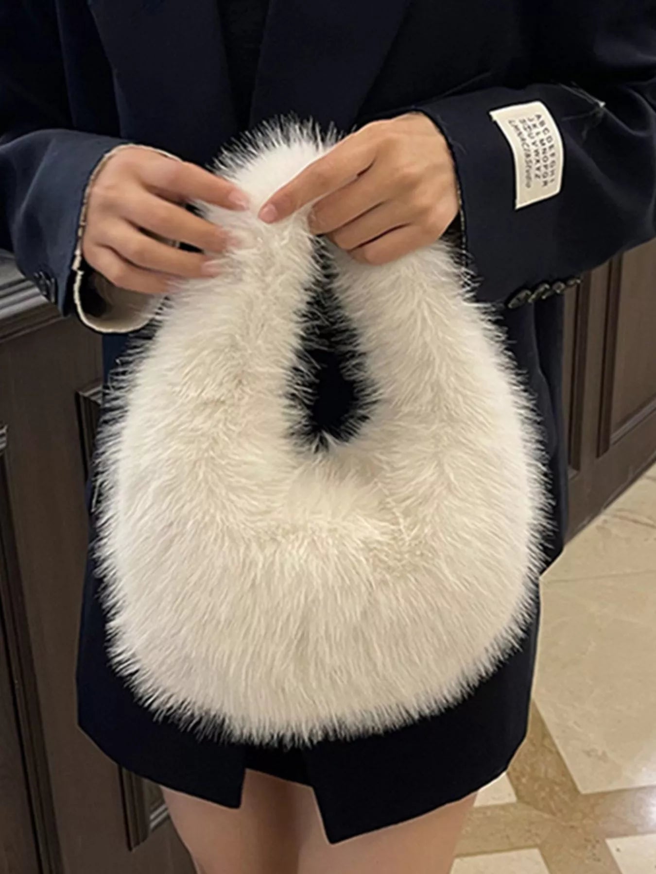 Person holding a fluffy white handbag with a black interior.