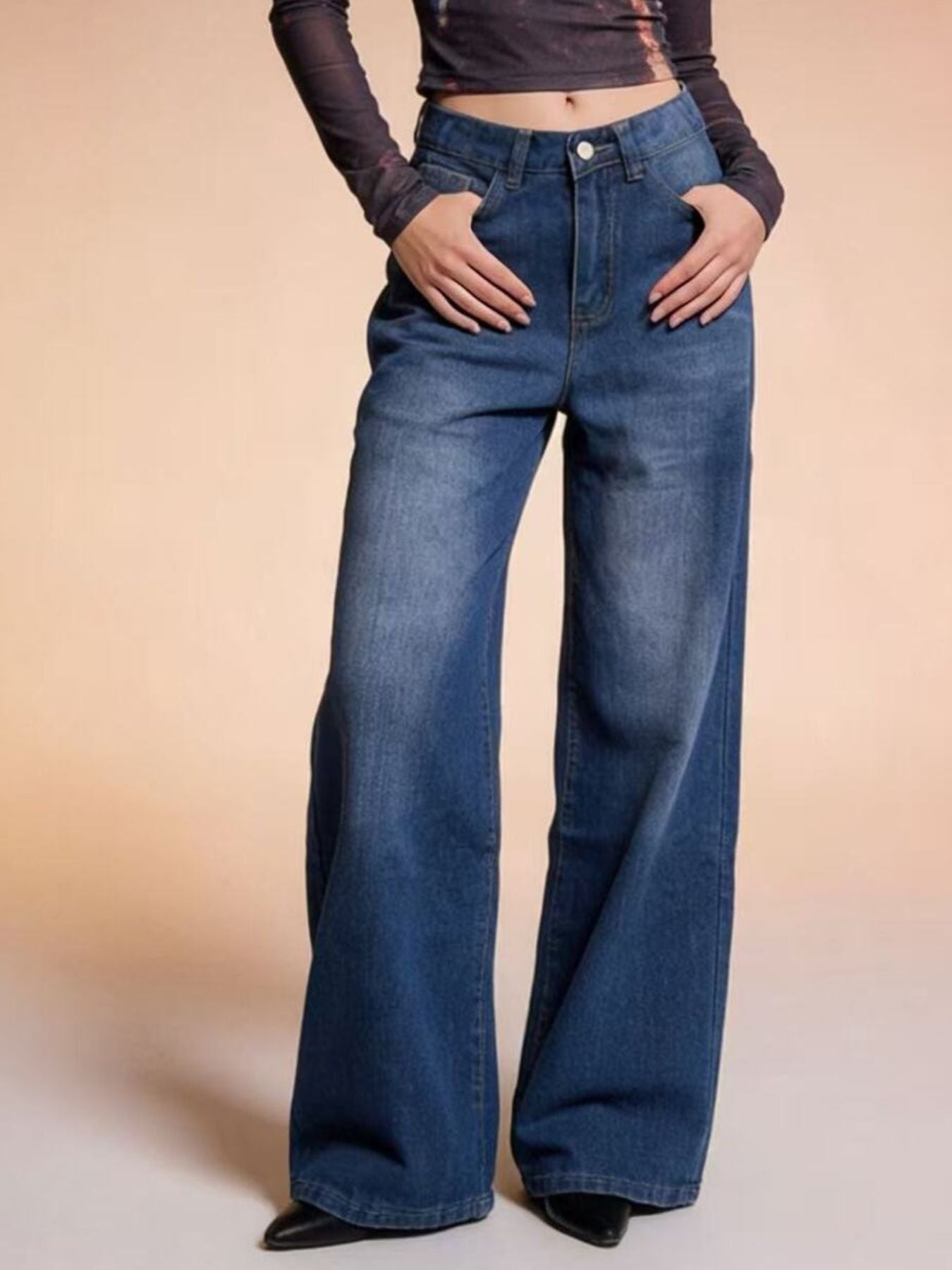 Person wearing blue flared jeans on a beige background