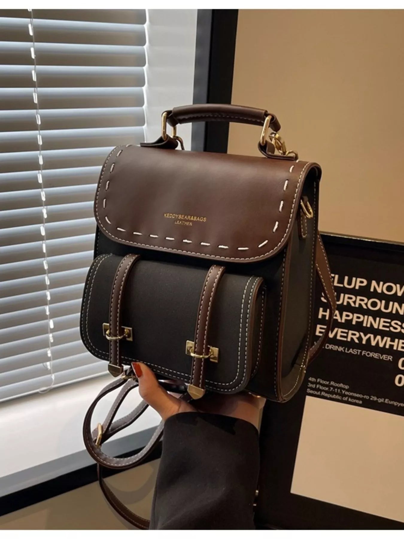 Brown leather backpack held by a hand with a blurred background