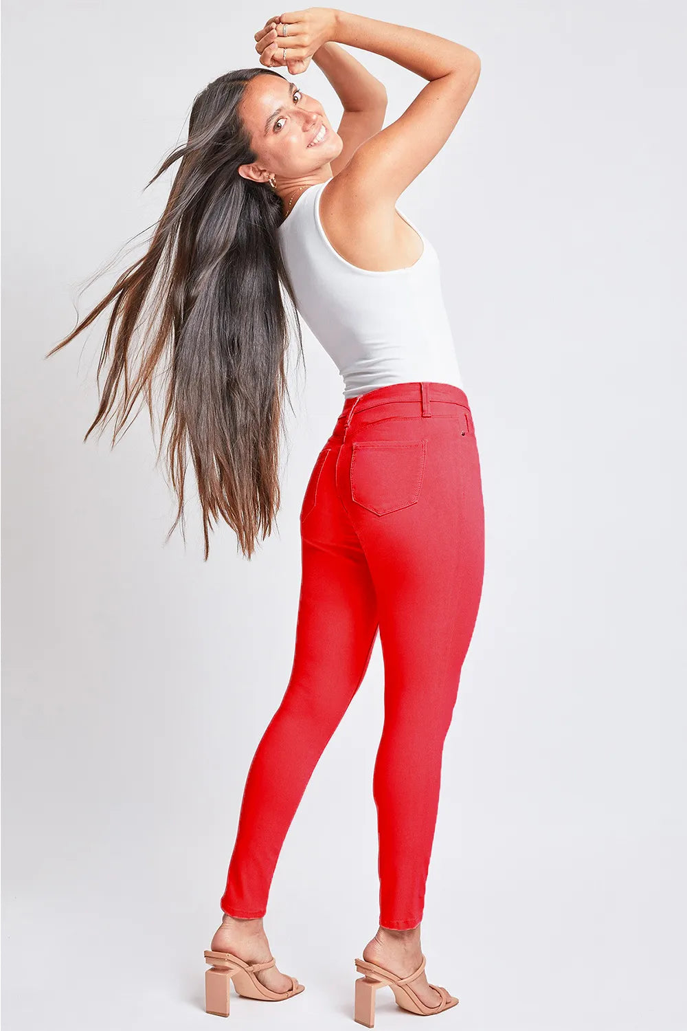Woman wearing red leggings and a white top on a light gray background