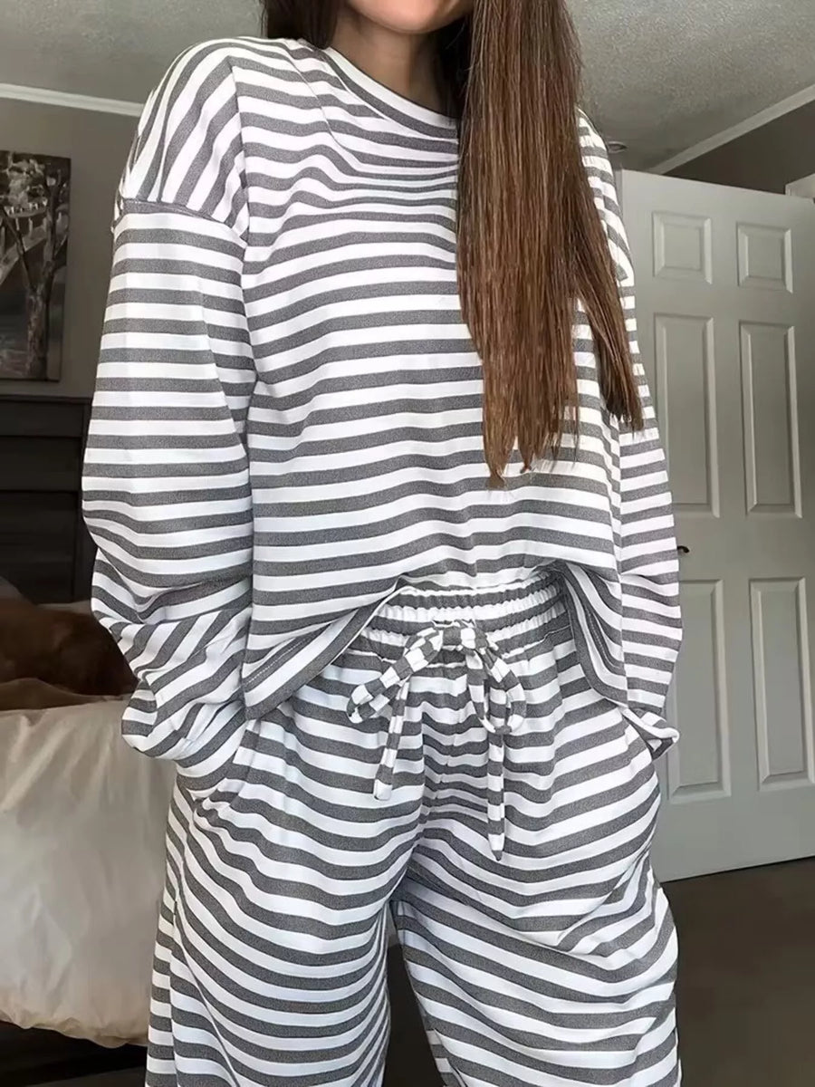 Person wearing a gray and white striped pajama set indoors.
