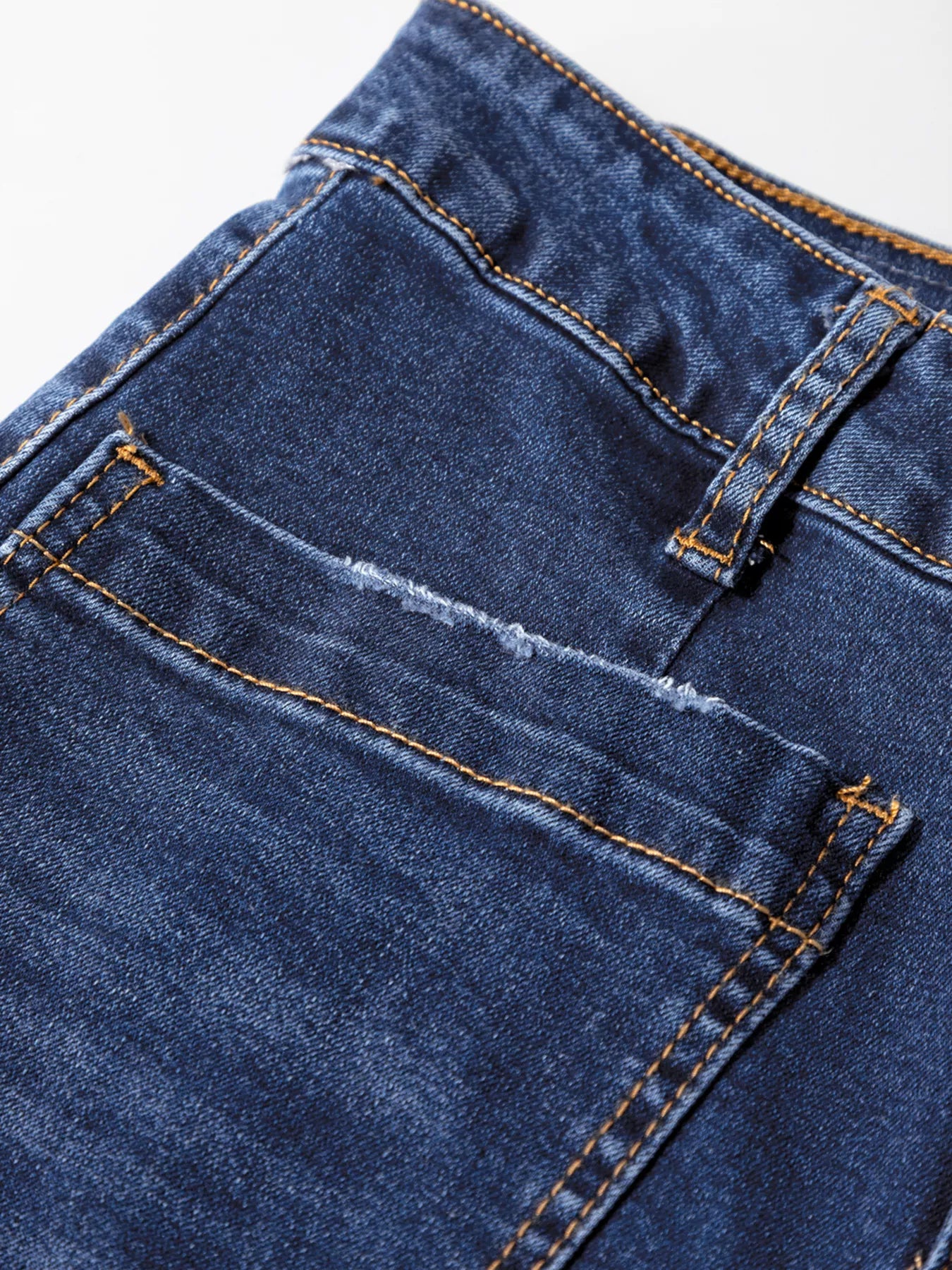 Close-up of blue denim fabric with stitching details on a white background
